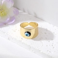 Gros plan détaillé d'une bague Evil Eye dorée sur un support en pierre texturée - Œil Noir