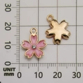 Pink sakura flower charm in gold finish with crystal inlay shown on a measuring scale - Pink Enamel Rhinestone Cherry Blossom (11896)