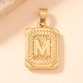 Macro view of gold-plated rectangular pendant featuring an embossed letter M detail - Letter M