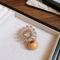 Primo piano di un elastico a spirale marrone con una perla giallo senape in una scatola - Elastico per capelli a spirale cavo telefonico con sfera in acrilico / Marrone