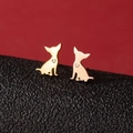 Gold chihuahua dog stud earrings with heart cutout on a textured black and red background - Sitting Chihuahua (777) / Rose Gold