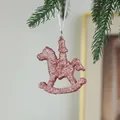 Pink glitter rocking horse Christmas ornament hanging on a green pine branch - Rocking Horse Style