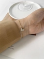 Detail of 18K gold butterfly bracelet featuring marquise zirconia on a woman's wrist - Clear
