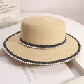 Detail of a beige straw boater hat featuring pearl embellishments and woven ribbon trim - Beige