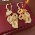 Detailaufnahme goldener Quastenohrringe mit hohlen Netzperlen und filigranen Metalldetails - Gold