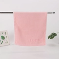 Pink cotton towel with LUTTO embossed texture hanging on a minimalist steel rod - Pink with Letter Embroidery (LUTTO)
