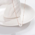 Elegante collana in oro rosa con ciondolo a perla bianca su un vassoio bianco - Oro rosa