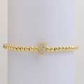 Detail of gold beaded stretch bracelet featuring a micro-pave zircon letter F charm - Letter F