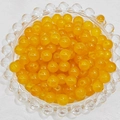 Macro detail of translucent orange glass beads for DIY jewelry making in a glass bowl - 4mm / Topaz