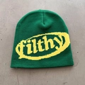 Close-up of green knitted beanie featuring yellow filthy lettering on textured surface - Green + Yellow Letters