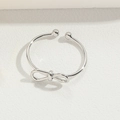 Verstellbarer silberner Schleifenring im minimalistischen Metalldesign auf weißem Leder - Knoten / Silber