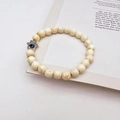 Macro shot of white turquoise beaded bracelet with silver Hamsa charm on book pages - White Textured Turquoise