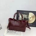 Burgundy woven leather tote bag with gold hardware shown with minimalist accessories - Burgundy