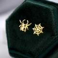 Detail of asymmetric gold spider and web stud earrings on a green velvet box - Asymmetric Spider and Web / Gold