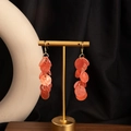 Detailed macro view of cascading amber resin bead earrings on a gold display stand - H3444-1 Style