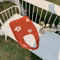 Detail der orangefarbenen Häkeltasche mit weißen Blumenmustern auf einer Gartenbank - Orange