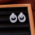 Close-up of silver knot earrings on black velvet display within a wooden frame box - Matte Silver Love Knot Stud Earrings