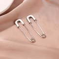 Close-up of silver geometric paperclip earrings on soft pink silk background - White K Pin Earrings (DZ-341)