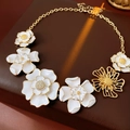Détail du collier à fleurs en émail vintage avec accents dorés et strass brillants - Fleur Blanche Dorée Avec Strass