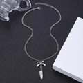 Macro shot of silver necklace featuring a bow, kitchen knife pendant, and Killing it text - Dark Bow Chef Knife Necklace White K (DZ-006)