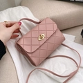 Pink quilted crossbody bag with gold twist lock and chain strap on neutral fabric - Pink