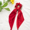 Detail van rode fluwelen haarelastiek met lang lint op een sierlijke tegel - Kerst Fluweel Wijnrood