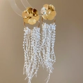 Detailansicht goldener Blumenohrringe mit kaskadierenden weißen Perlenquasten auf Ständer - Weiß