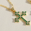 Macro shot of gold cross pendant necklace with green and clear zircon stones inlay - Green Zirconia