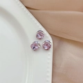 Pink multi-faceted crystal charms on a white ceramic plate with soft silk background - Crystal Purple