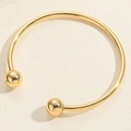 Gedetailleerd macro-aanzicht van de goudkleurige metalen open armband met twee bolvormen - Koperen Kralen Armband Goud Stijl (SL0194-2)