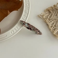 Detailed macro of handmade acetate hair clip with vintage marble texture and logo - Green Brown Pattern