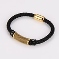 Detalle de una pulsera de cuero trenzado negro con cierre magnético dorado y tubo de metal - Dorado