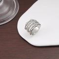 Detailed view of silver skeleton hand bone ring on a white ceramic plate backdrop - US 6 / Steel
