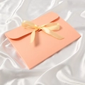 Elegant apricot pink envelope gift box with a satin bow on a white silk background - Pink