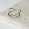 Detailaufnahme eines silbernen verschlungenen Doppelrings auf einer Travertinsteinplatte - US 6 / Silber