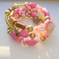 Pulsera bohemia multicapa con cuentas rosas, detalles de madera y colgante de flor dorada - Rosa