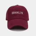 Detailed close-up of white Brooklyn embroidery on a burgundy cotton baseball cap - Burgundy