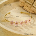 Dettaglio di un bracciale dorato con fiori rosa e dimensioni su un vassoio di pietra - Rosa (NMSB-F335-5)