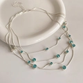 Detail van zilveren gelaagde ketting met blauwe edelstenen op een wit keramisch bord - Zilver-Blauw