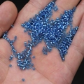 Hand holding transparent blue 2mm glass seed beads for DIY jewelry making - 2mm / 15g / Blue