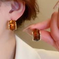 Close-up of amber-toned wide hoop earrings with gold trim on model for sizing - Style 84# S925 Silver Pin Gold Amber Resin Hoops