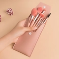 Rosa Reise-Make-up-Pinsel-Set in passender PU-Ledertasche, in der Hand gehalten - 8-Teiliges Set Mit PU-Tasche / Korallenrosa