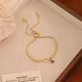 Bracciale regolabile con perline dorate, ciondolo lettera D e amuleto malocchio - Lettera D
