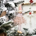Pink and white Christmas angel ornament with fringe dress hanging on a snowy pine tree - Pink