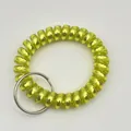 Macro view of bright yellow spiral plastic wrist coil keychain with silver metal ring - Metallic Yellow