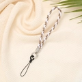 Detail of woven brown and white phone wrist strap with silver metal ring on fabric - Khaki