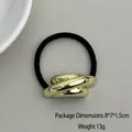 Elastic hair tie featuring a twisted gold metal geometric charm and black cord - Oblique Triple Tube