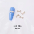 Détail de bijoux de nœuds dorés 8x5mm pour nail art avec strass sur tissu en soie blanc - Nœud Papillon Doré avec Strass (8193)