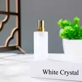 White crystal perfume spray bottle with gold pump head on white display pedestal - White Crystal