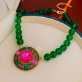 Vista macro di una collana vintage con perline verdi e pendente con gemma rosa - Collana con perline / Verde